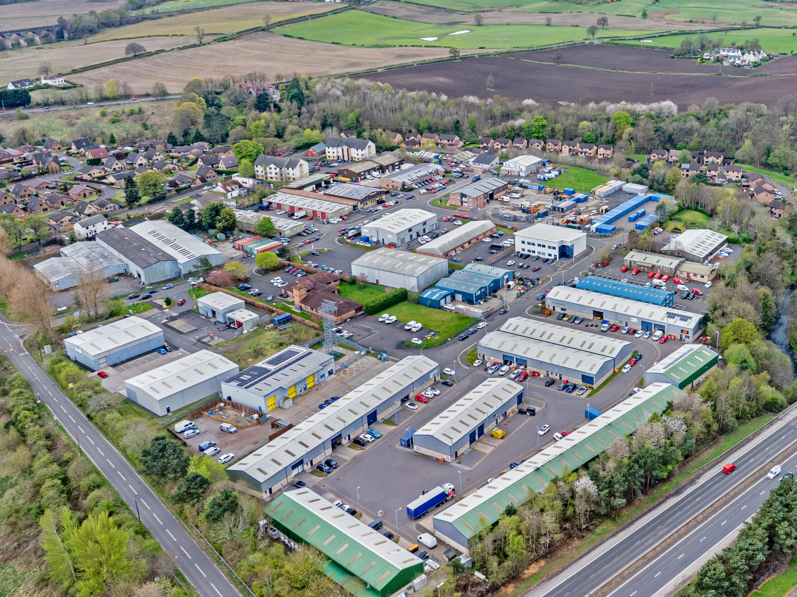 Mill Road Industrial Estate – Aerial View, Linlithgow, West Lothian High-resolution aerial drone photograph of Mill Road Industrial Estate in Linlithgow, West Lothian. The image captures the estate’s layout, including self-storage units, industrial buildings, and nearby transport links.